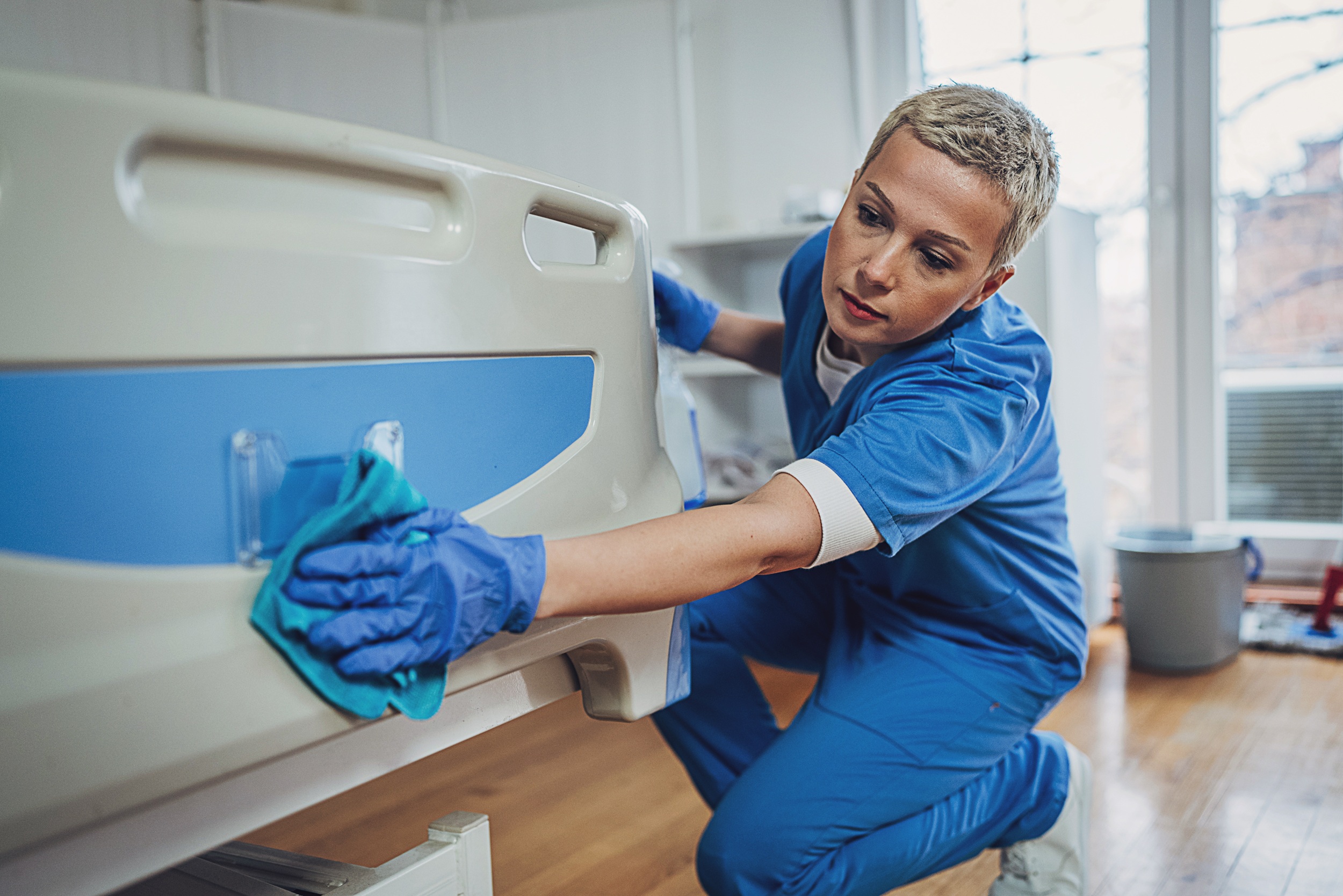Vrouw die een bed schoonmaakt in een verzorgingsinstelling.