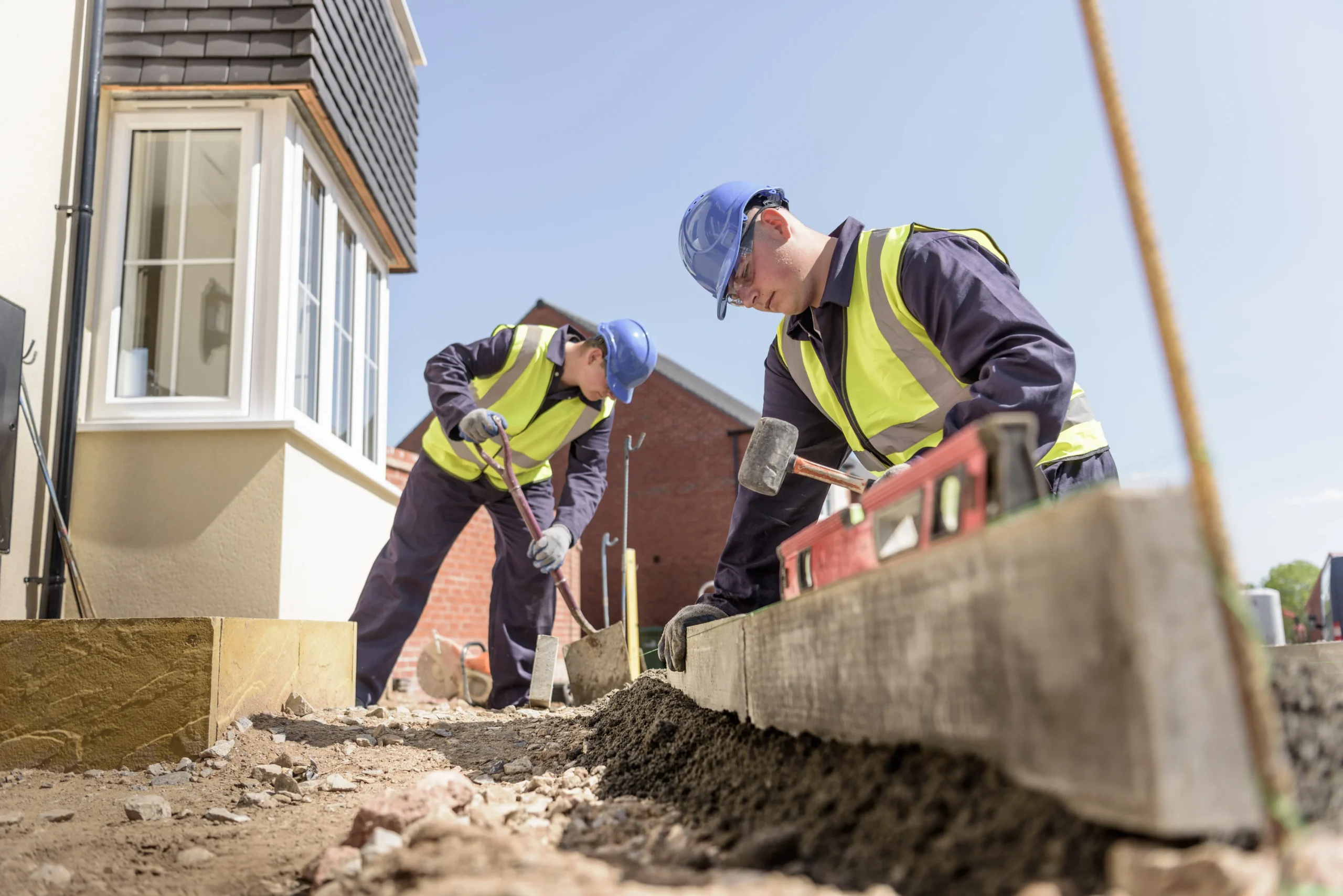 Twee werkers in de bouw met een schep en een hamer.